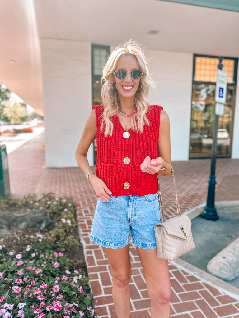 Red sweater vest with gold buttons and jean shorts